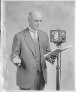 Gleason L. Archer (President, 1937-1948, and Founder of Suffolk University) standing in front of NBC microphone, reading from script
