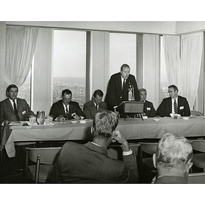 John U. Harris, Jr., speaking from the podium while other board members sit beside him during a Boys' Club meeting