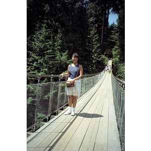 Young woman stands on the Capilano Suspension Bridge in the rain forest of British Columbia