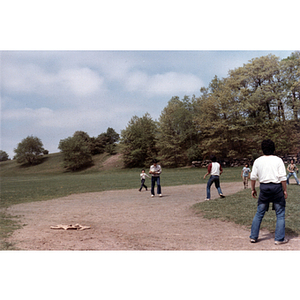 Man holds a kickball while others stand nearby during a kickball game