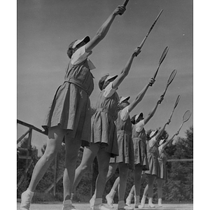 Boston-Bouvé students stand in a row with tennis racquets in the air