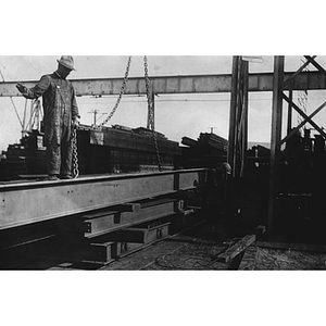 Workers of the New England Structural Co. stand on beams to repair wires