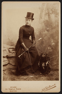 Full-length portrait of Lesley Dillingham Bangs, seated on a studio prop, facing front, holding a riding crop and her dog's leash, Boston, Mass., 1889