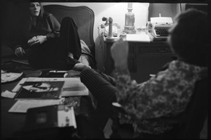 Judy Collins, seated on a bed at the Beverley Hills Hotel, talking with an unidentified man