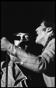 John Lennon and Paul McCartney (partially obscured) performing with the Beatles at D.C. Stadium