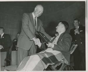 President Dwight D. Eisenhower handing a plaque to an unidentified man in a wheelchair