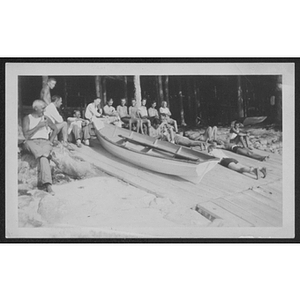 People seated at edge of beach with canoes