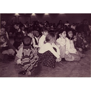 Children sitting on the floor at the Jorge Hernandez Cultural Center watch a performance.