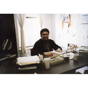 Inquilinos Boricuas en Acción employee seated at his desk covered with paperwork.