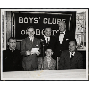Four men and two boys pose in front of a microphone at a Boys' Clubs of Boston awards event