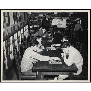 Pairs of boys play checkers in a library