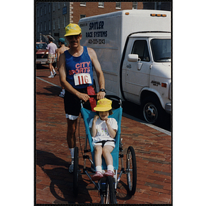 A runner poses with a child in a carriage during the Bunker Hill Road Race