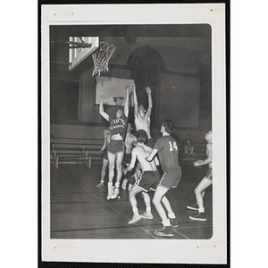 Teenage boys vie for the ball near the basket during a basketball game