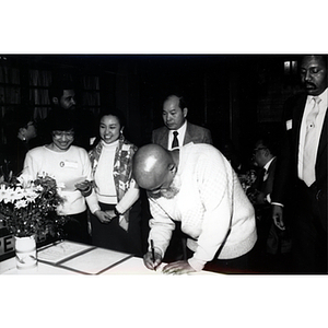 Civil rights activist Chuck Turner signs an agreement at a Chinese Progressive Association event