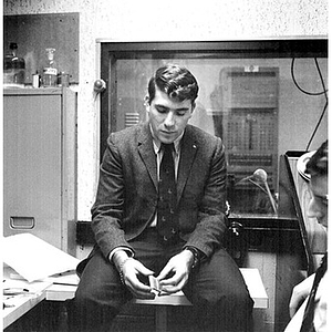 Young man sitting on a table playing with a matchbook at the WNEU studio