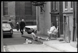 Women and a dog sitting in lawn chairs on a side street in Boston's North End