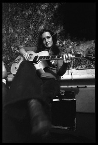 Bonnie Raitt seated backstage, playing guitar