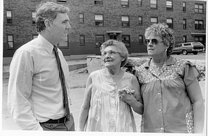 Mayor Raymond L. Flynn speaking with two unidentified women in front of a Boston public housing unit