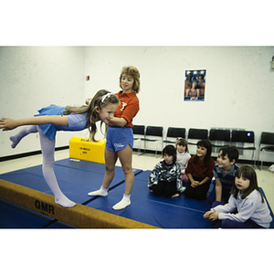 YMCA instructor assisting a young girl on the balance beam