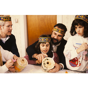 Child being helped with a craft while wearing a feather headband