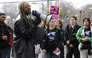 Justice for Jason rally at UMass Amherst: Amilcar Shabazz, Chair of UMass Afro-American Studies, speaks near a flower-filled fence, to students and staff who rally in support of Jason Vassell