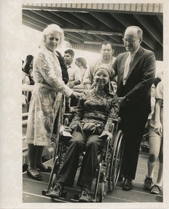 Woman in wheelchair assisted on ramp