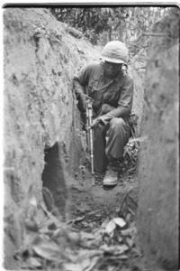 Negro soldier of the 1st Infantry Division searching a Vietcong trench.