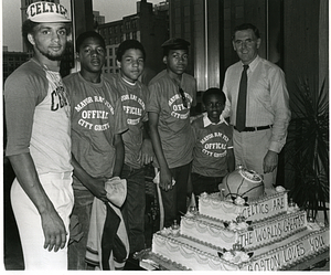 Mayor Raymond L. Flynn behind Boston Celtics cake with four unidentified boys wearing "Official City Greeter" t-shirts