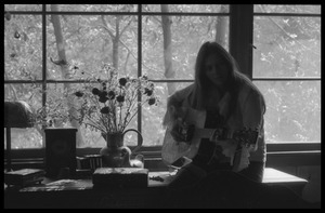 Judy Collins playing guitar while silhouetted against a window in Joni Mitchell's house in Laurel Canyon