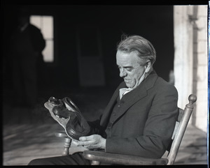 William F. Clapp, seated, examining a model of a snake