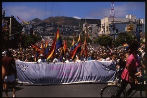 Massive crowd approaching during the San Francisco Pride Parade, carrying pride flags and banner reading 'Rightfully proud'