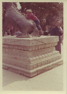 Child climbing on a bronze qilin at the Summer Palace in Beijing, China