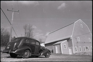 Car parked in front of unidentified gambrel-roofed barn