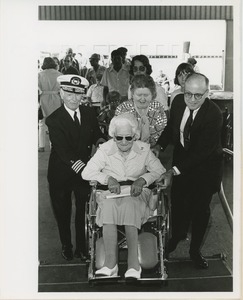 Woman in wheelchair assisted on gangplank