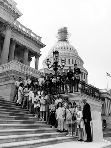 Congressman John W. Olver (right) and visitors, posed on the steps of the United States Capitol building (scaffolding on top of dome)