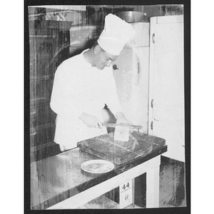 Chef slicing a loaf of bread in a kitchen