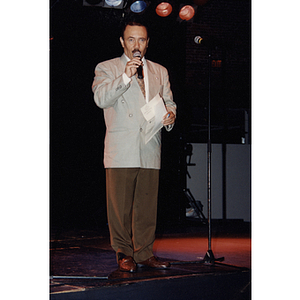 A man speaks into a microphone on stage at the Festival Puertorriqueño