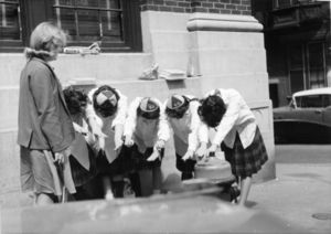 Suffolk University first-year students wearing beanies as they bow to an upperclasswoman