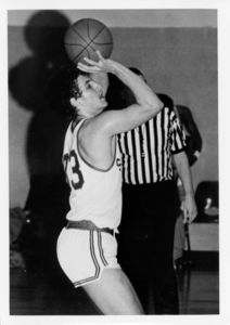 Suffolk University men's basketball player Chris Tsiotos goes up for a shot during a game, 1975