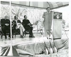 Robsham Theatre exterior: groundbreaking, J. Donald Monan listening to unidentified man at podium