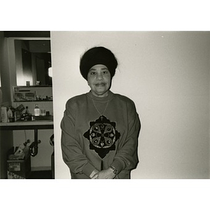 Woman posing for a portrait against a blank wall, with a sink visible in the background.