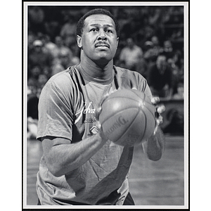 Former Boston Celtics player and head coach M.L. Carr holding a basketball and looking up at a fund-raising event held by the Boys and Girls Clubs of Boston and Boston Celtics