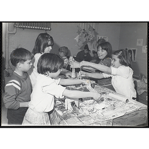 Four girls and a boy stand around a table, working on projects for their art class at the Boys and Girls Clubs of Boston