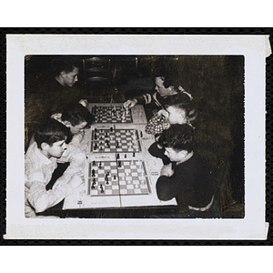 Three pairs of boys play chess at a bench