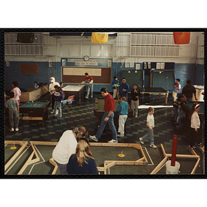 Two girls play on an indoor miniature golf course in the Charlestown Clubhouse