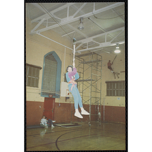 A girl hangs on to a climbing rope in a gymnasium