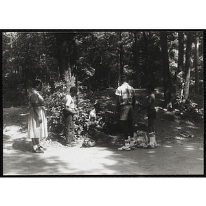 A Small group of children and adults in a wooded clearing at a camp