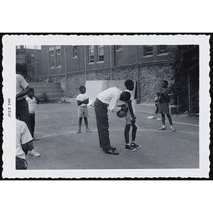 A man attaches a balloon to a boy's waist for a game as other boys look on during Tom Sawyer Day