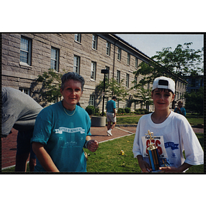 A boy holding a trophy poses with a woman at the Battle of Bunker Hill Road Race