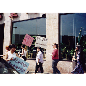 Five female demonstrators with protest signs picketing for back wages outside of Dynasty Restaurant